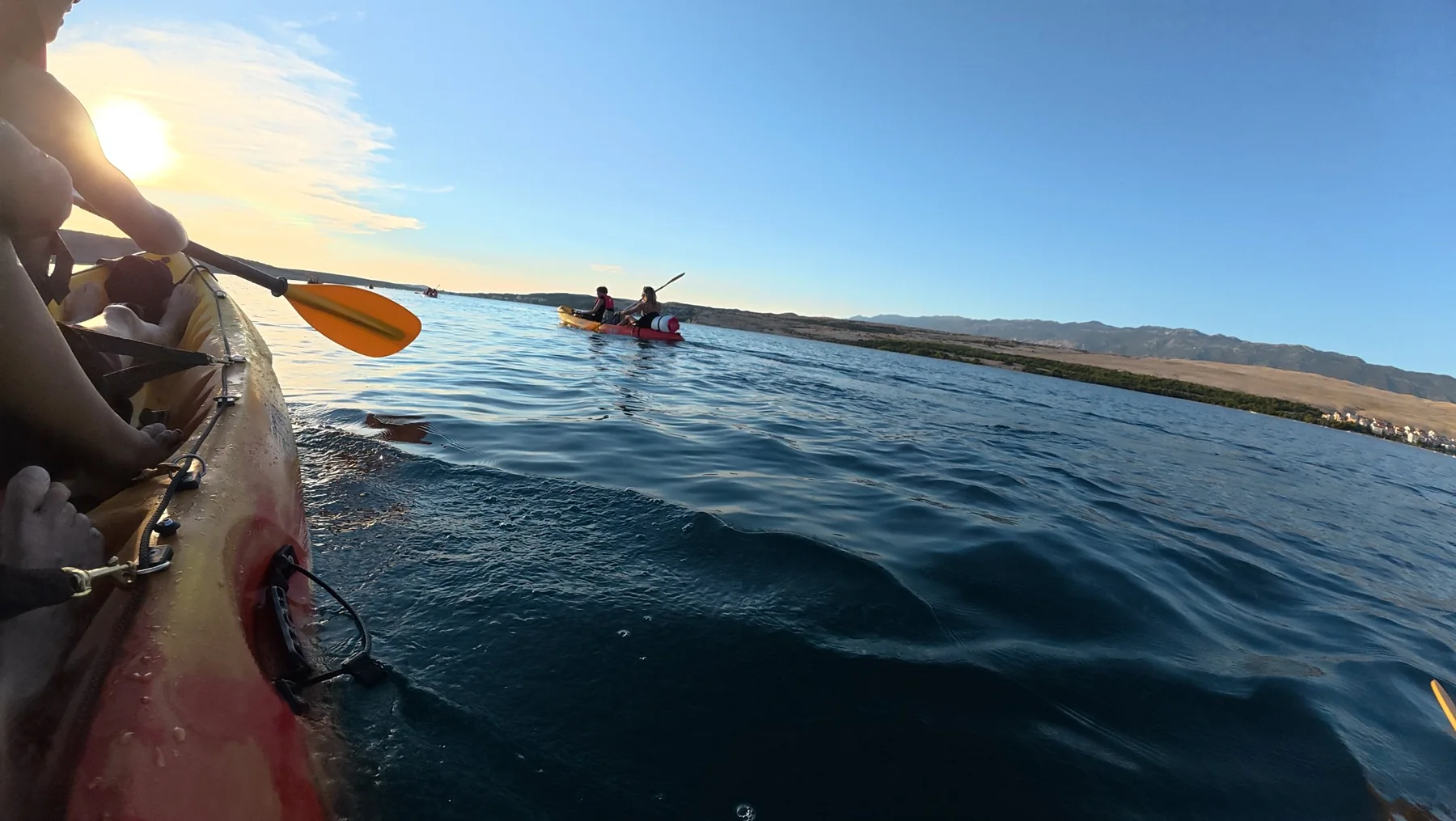 Kayak crossing the sea with Pag landscape behind